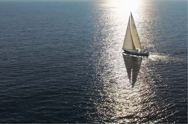 Traditional sailing dhow crossing open sunlit sea